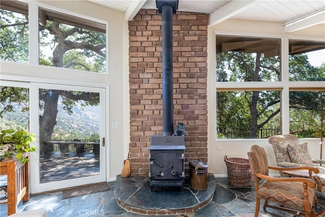 interior space with a wood stove and beam ceiling