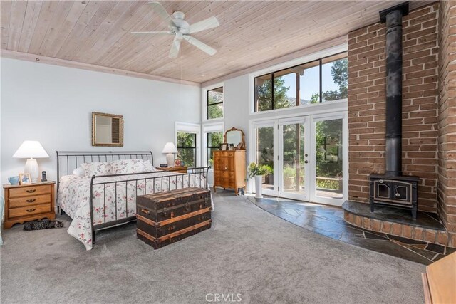 bedroom featuring ceiling fan, carpet, a wood stove, and wooden ceiling