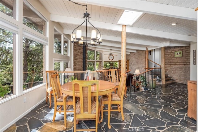 dining space featuring plenty of natural light, brick wall, an inviting chandelier, and lofted ceiling with skylight