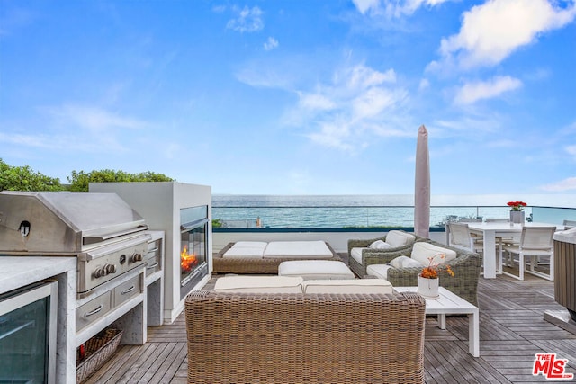 view of patio with an outdoor hangout area, a grill, a deck with water view, and exterior kitchen