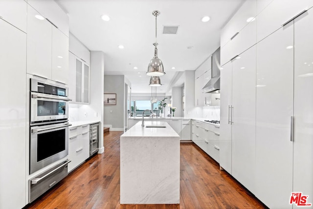 kitchen with pendant lighting, white cabinets, a center island with sink, and dark hardwood / wood-style flooring