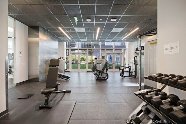 exercise room featuring a drop ceiling, floor to ceiling windows, and french doors