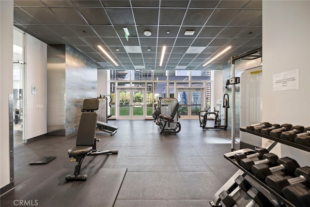 exercise room featuring expansive windows, french doors, and a drop ceiling