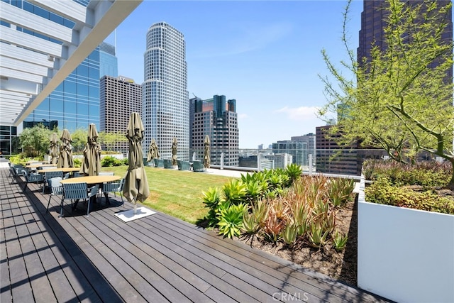 wooden terrace featuring a lawn, a city view, and outdoor dining area