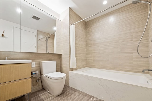 full bathroom with vanity, tile walls, shower / bath combo with shower curtain, and toilet