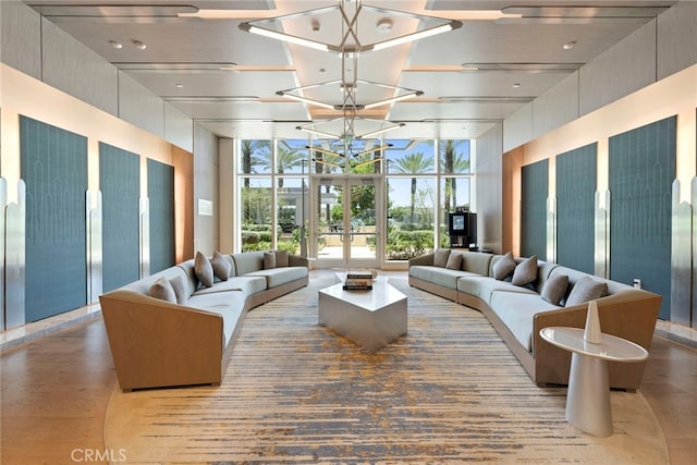 living room with a wall of windows, hardwood / wood-style floors, a towering ceiling, and an inviting chandelier