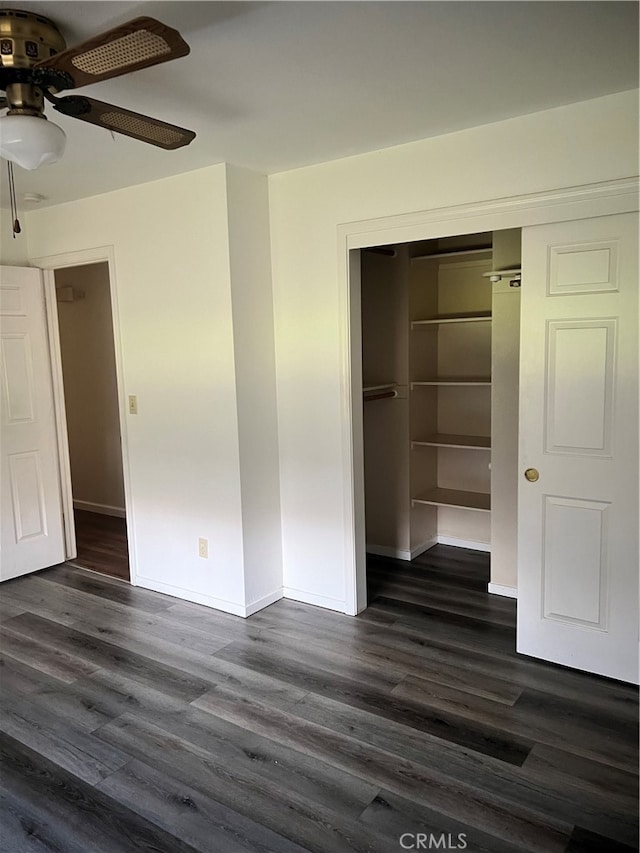 unfurnished bedroom featuring ceiling fan, a closet, and dark wood-type flooring