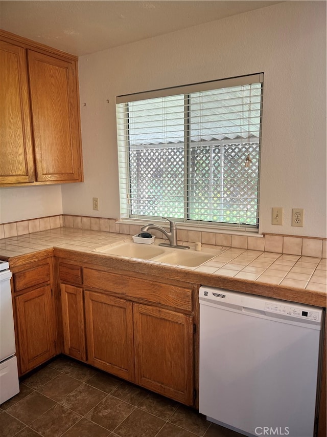 kitchen featuring dark tile patterned floors, white appliances, tile counters, and sink