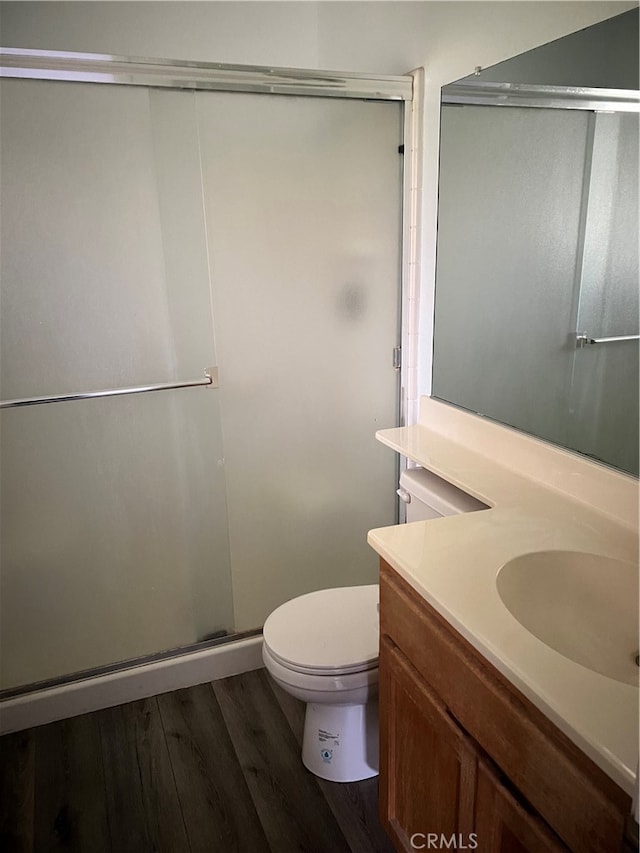 bathroom with walk in shower, hardwood / wood-style floors, vanity, and toilet