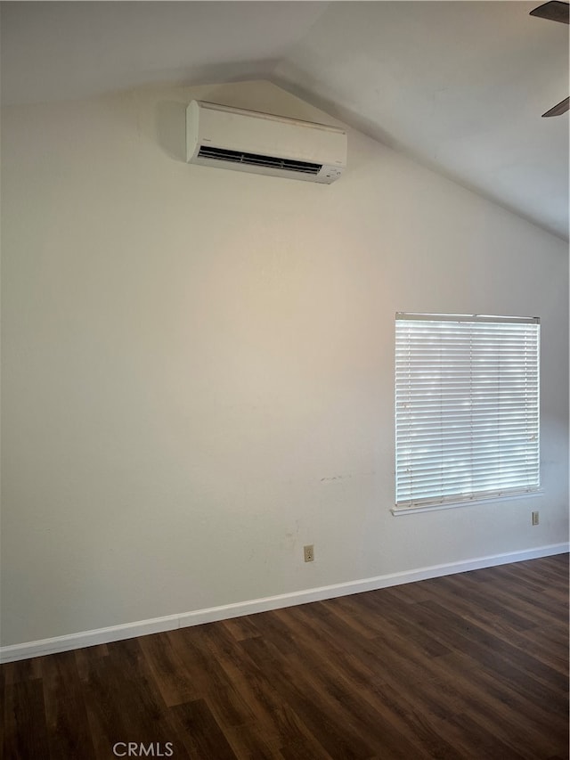 spare room featuring vaulted ceiling, dark wood-type flooring, and an AC wall unit