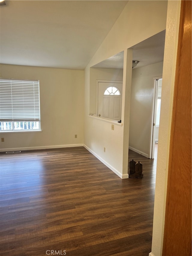 spare room featuring lofted ceiling and dark wood-type flooring