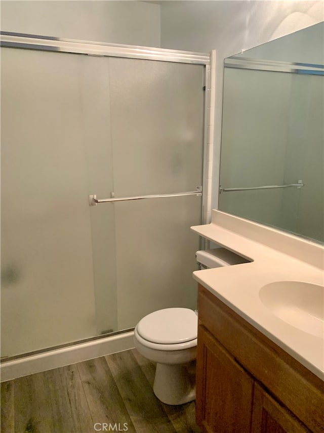 bathroom with vanity, a shower with shower door, toilet, and hardwood / wood-style flooring