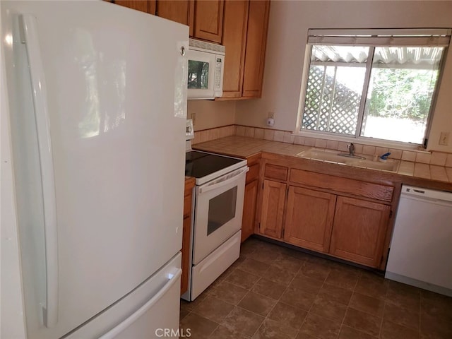 kitchen with white appliances, sink, and tile countertops