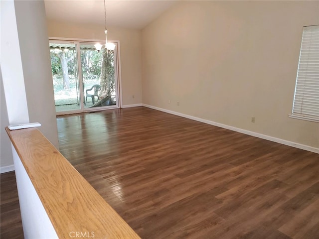 spare room featuring a notable chandelier and dark hardwood / wood-style flooring