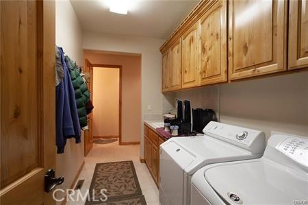 clothes washing area with washer and dryer and cabinets