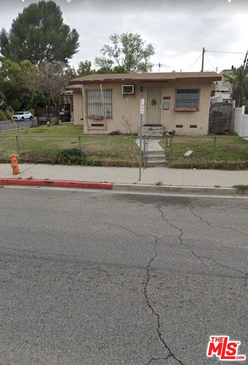 view of front of property with a front yard and a wall unit AC