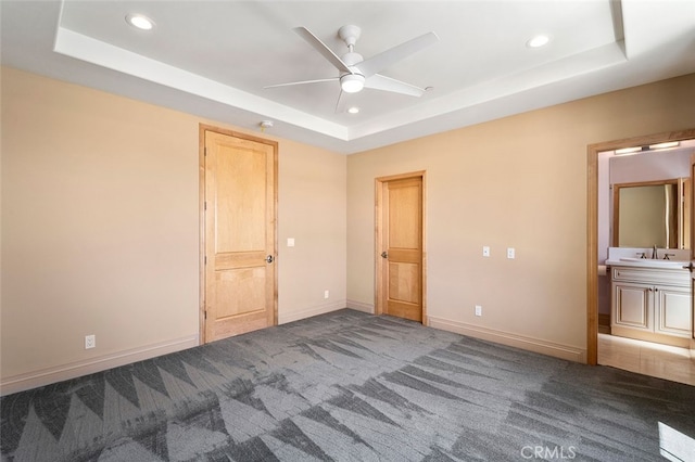 unfurnished bedroom featuring ceiling fan, carpet floors, and a tray ceiling