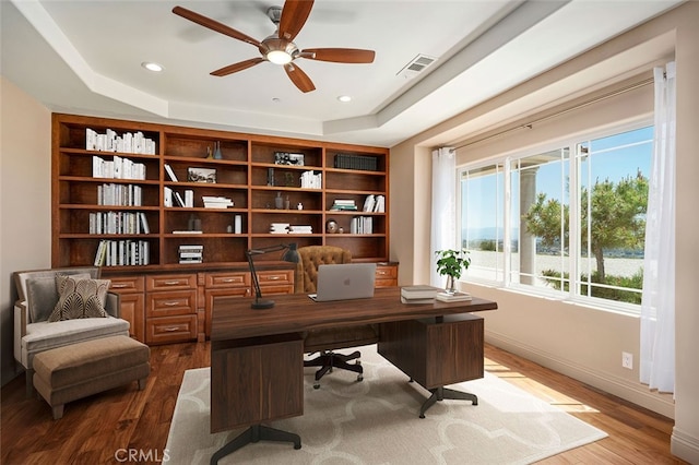 office area with wood-type flooring, a tray ceiling, and ceiling fan