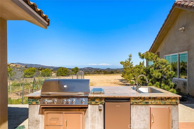 view of patio / terrace featuring a grill, an outdoor kitchen, sink, and a mountain view