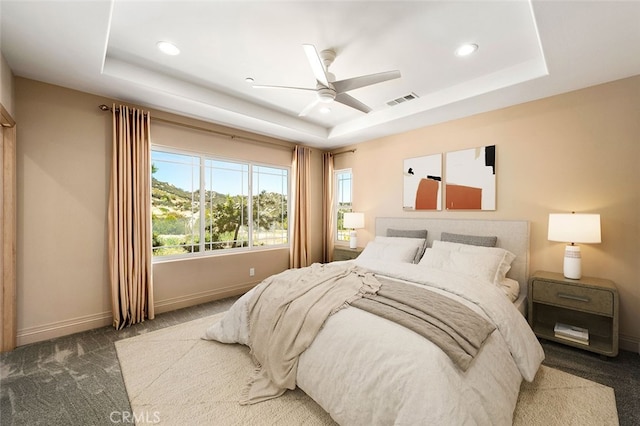 carpeted bedroom with a tray ceiling and ceiling fan