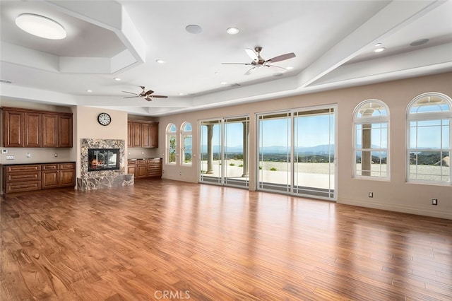 unfurnished living room featuring a stone fireplace, ceiling fan, and light hardwood / wood-style flooring