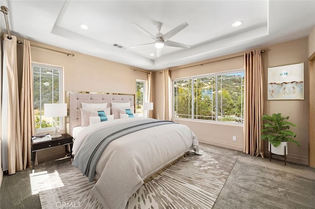 carpeted bedroom with a tray ceiling and ceiling fan