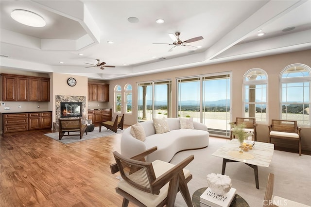 living room with ceiling fan, a tray ceiling, and a healthy amount of sunlight