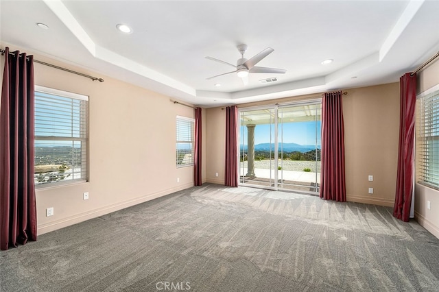 unfurnished room featuring a mountain view, ceiling fan, a raised ceiling, and carpet floors