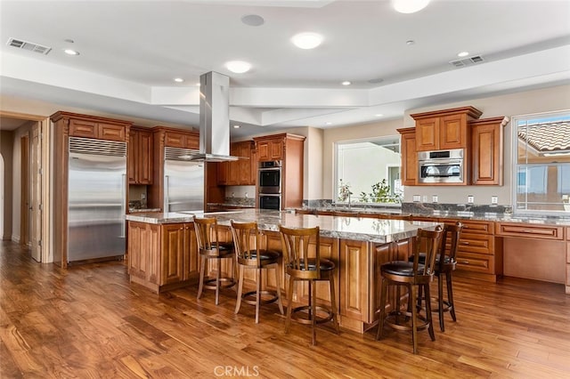 kitchen featuring a large island, stainless steel appliances, wood-type flooring, and a breakfast bar