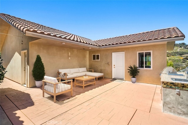 back of house with an outdoor living space, an outdoor kitchen, a patio area, and sink