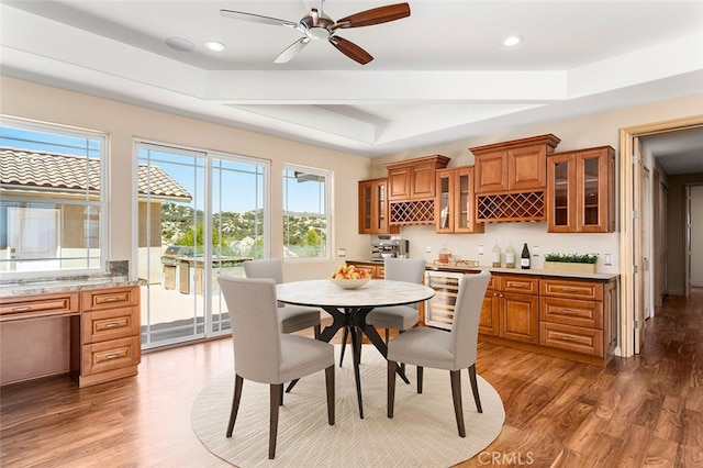 dining space featuring ceiling fan, a tray ceiling, and dark hardwood / wood-style floors