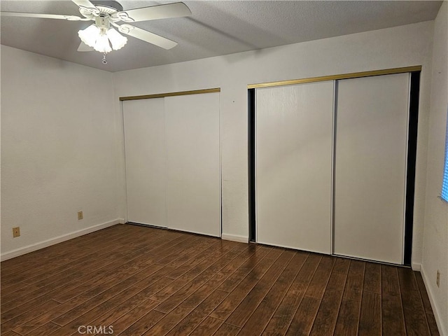 unfurnished bedroom featuring multiple closets, ceiling fan, baseboards, and wood finished floors