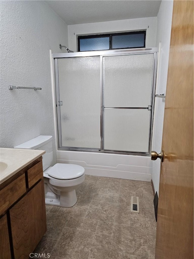 bathroom with visible vents, a textured wall, toilet, enclosed tub / shower combo, and vanity