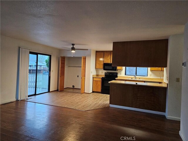 kitchen featuring hardwood / wood-style floors, ceiling fan, a textured ceiling, black appliances, and sink