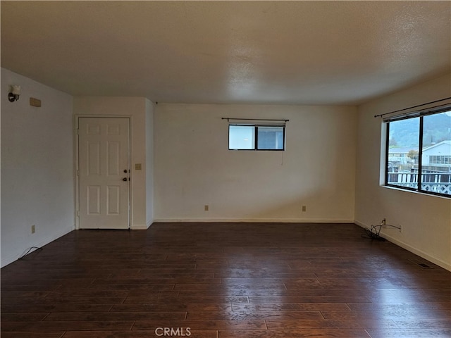 unfurnished room featuring a textured ceiling and dark hardwood / wood-style flooring