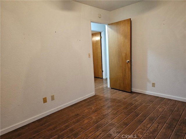 unfurnished room featuring dark wood-style flooring and baseboards