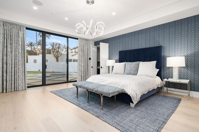 bedroom featuring access to outside, french doors, a chandelier, and hardwood / wood-style floors