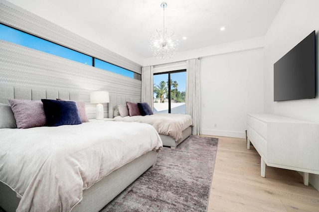 bedroom featuring light hardwood / wood-style floors, access to exterior, and a notable chandelier