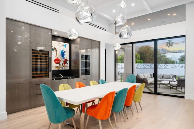 dining area with light hardwood / wood-style flooring and beamed ceiling