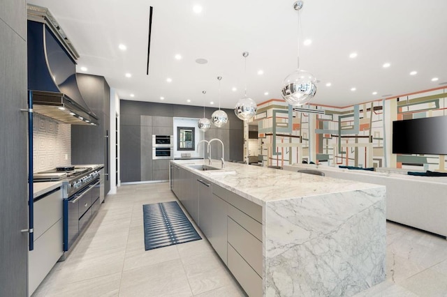 kitchen featuring a large island, ventilation hood, gray cabinetry, gas stove, and decorative light fixtures