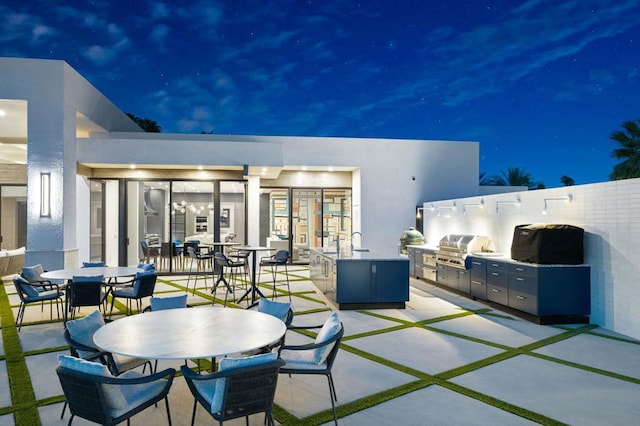 patio at twilight featuring exterior kitchen, sink, and area for grilling