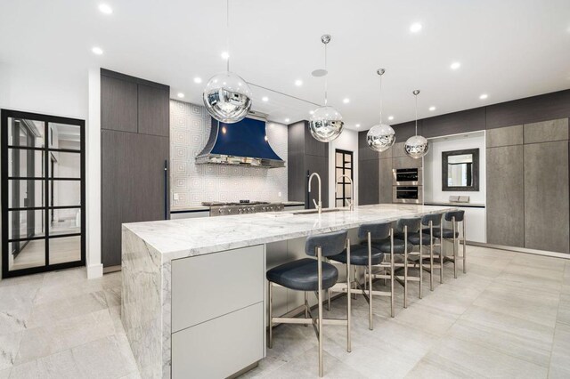 kitchen featuring a large island, decorative backsplash, decorative light fixtures, a kitchen breakfast bar, and sink