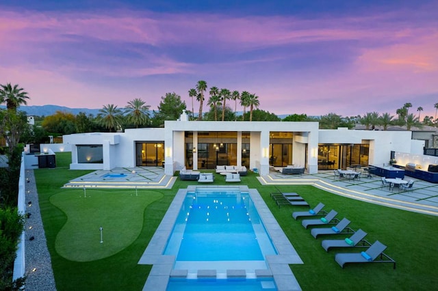 back house at dusk with a patio area and an outdoor living space