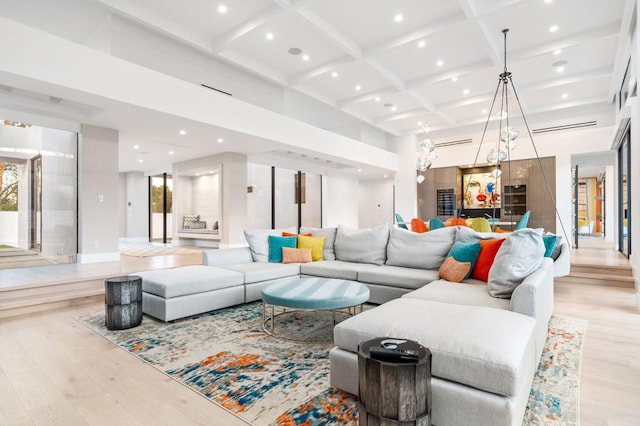 living room with light hardwood / wood-style flooring, beam ceiling, a towering ceiling, and coffered ceiling