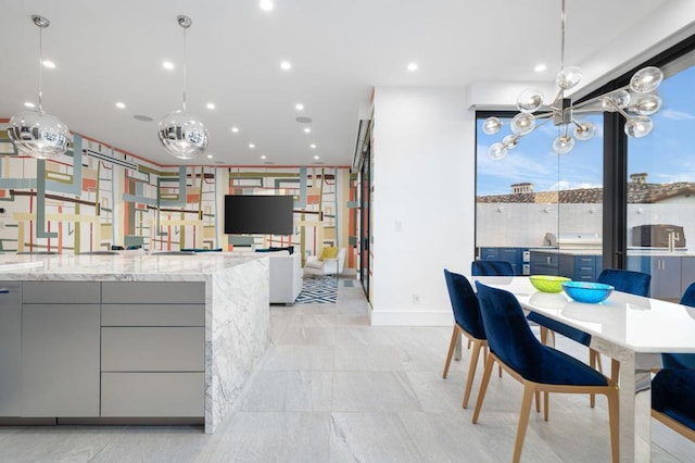 kitchen with gray cabinetry, hanging light fixtures, and light stone countertops