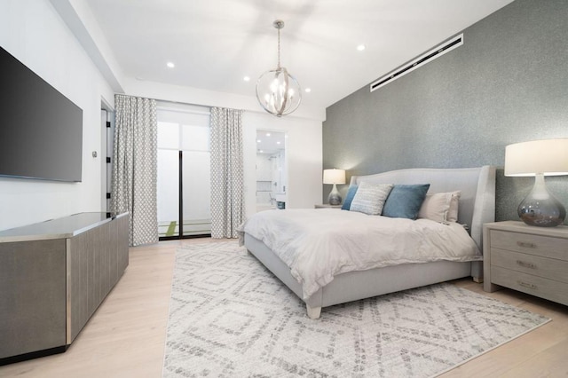 bedroom featuring ensuite bath, a notable chandelier, and light hardwood / wood-style flooring