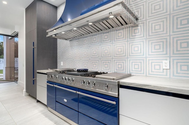 kitchen featuring high end range, light tile patterned floors, and custom range hood