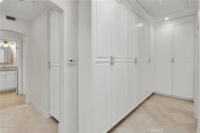 hallway with light tile patterned flooring and ornamental molding