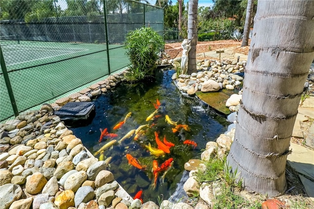 view of sport court with a small pond