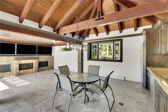 dining area featuring wooden ceiling, a stone fireplace, and lofted ceiling with beams